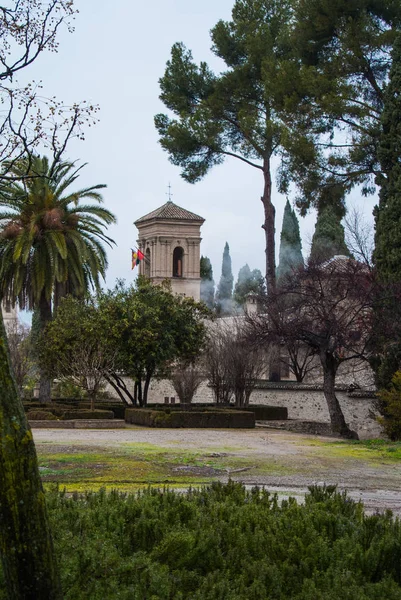 Granada, spanien - 10. februar 2015: ein blick auf einen turm mit fahnen an einem regnerischen nebeltag im hof der alhambra, granada, andalusien, spanien. — Stockfoto