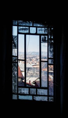 Tiflis 'in merkezinde eski bir evin ezilmiş füme penceresi ve şehir manzarası.