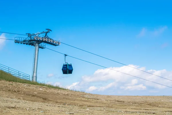 Uma vista para uma cabine de teleférico moderna azul movendo-se para o topo da montanha, parque natural de Bucegi, Sinaia, Romênia . — Fotografia de Stock