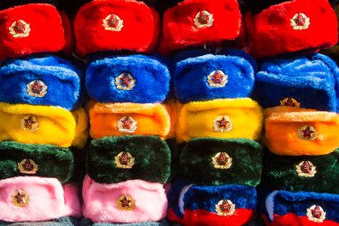 Eski Arbat caddesindeki sokak pazarında farklı renklerde Rus kış şapkaları ve ordu amblemleri, Rusya 'dan ikonik popüler hatıra..