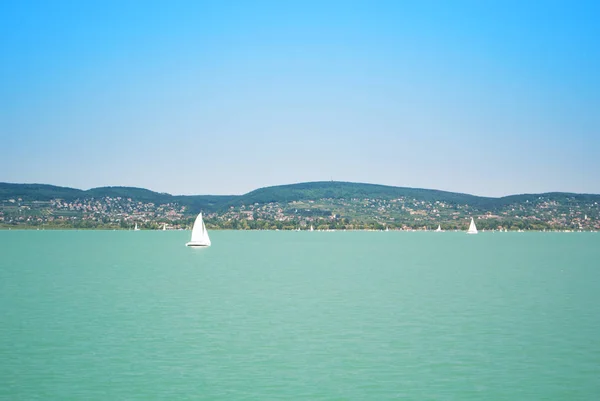 Uma vista de um navio para a água brilhante do lago Balaton e um iaque branco — Fotografia de Stock