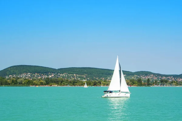 A view from a ship to bright Balaton lake water and a white yach — Stock Photo, Image