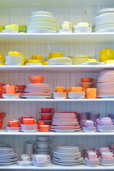 Bright colorful yellow red dishes, plates and cups standing on w