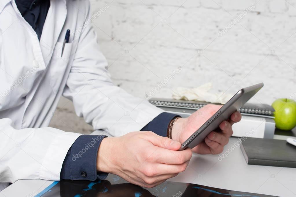 Doctor filling medical online form in the laptop tablet. The works at the hospital