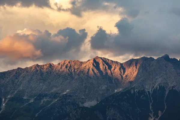 Dağlar tepeler turuncu bulutlu gün batımı ışık altında taş.