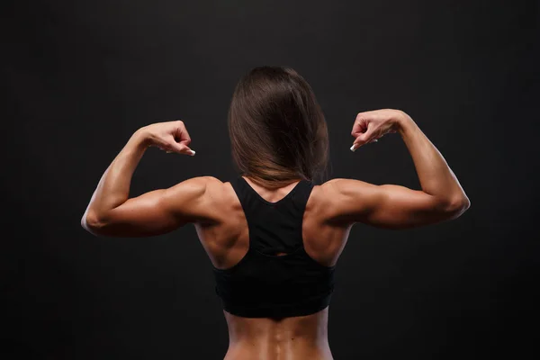 Sportovní mladá žena ukazuje svaly zad a rukou — Stock fotografie