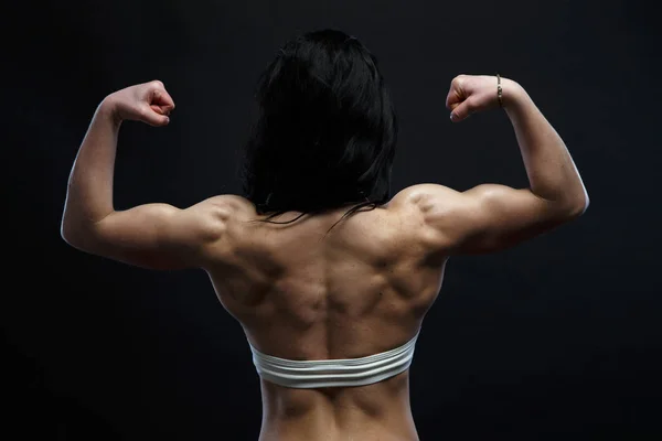 Atletische jonge vrouw tonen spieren van de rug en de handen — Stockfoto
