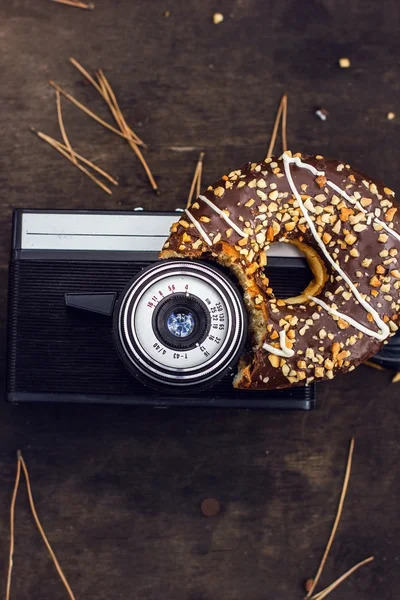 Ретро-винтажная кинокамера на деревянном фоне с донатом — стоковое фото