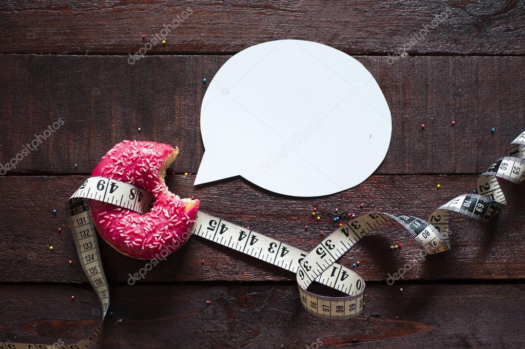 Donut with measuring tape and speech bubble on wooden background