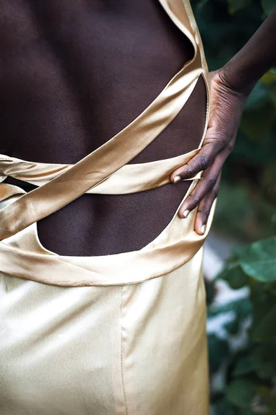 Indietro di modello di pelle scura nel vestito di raso d'oro — Foto Stock