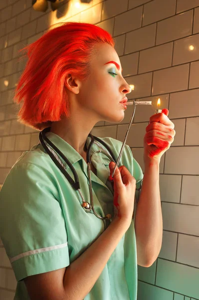 Redhead medical student in scrubs lights up a cigarette