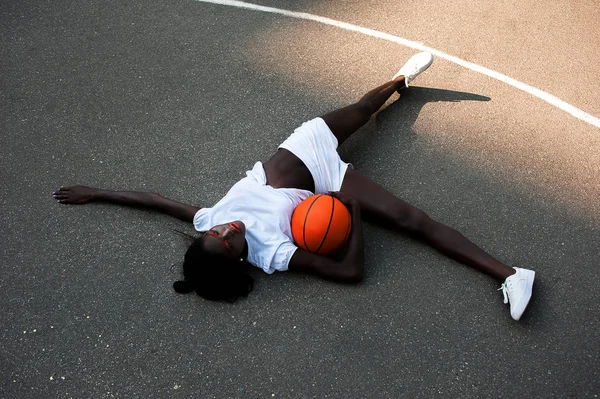 Modello afro-americano sportivo in bianco con basket su asfalto — Foto Stock