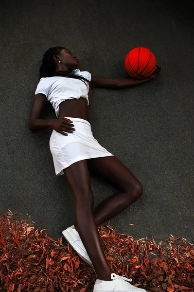 Slim giovane afro-americano ragazza in posa con pallacanestro su asfalto — Foto Stock
