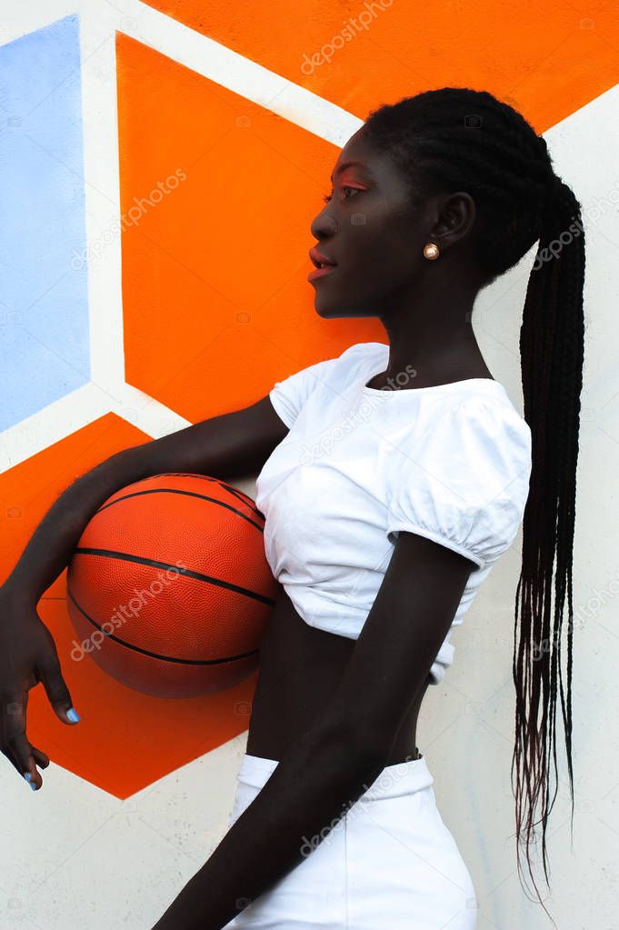 Beautiful ethnic Nigerian sportswoman in white with a basketball