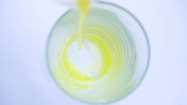 Şeffaf cam beyaz zemin üzerine dökülen sarı turuncu yavaş süreci.