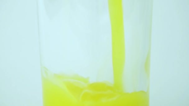 Proceso Lento Verter Naranja Amarilla Vidrio Transparente Sobre Fondo Blanco — Vídeos de Stock