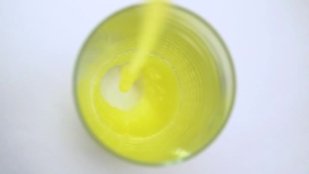 白の背景上の透明なガラスに注ぐ黄色オレンジのゆっくりとしたプロセス — ストック動画