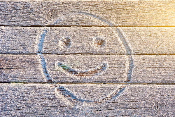 Smiley face hand drawn on the frozen bench in the Park