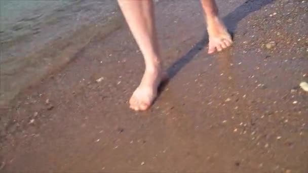 若い女の子の足がビーチを歩いている。ビーチで愛する。足の閉鎖。ストックビデオ — ストック動画