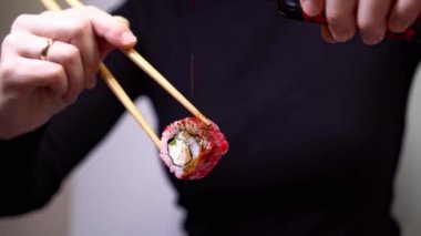 Kız sushi soya sosu koyuyor.
