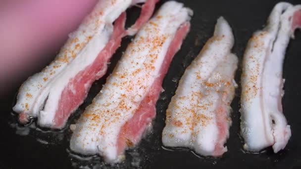 Färsk bacon sprutar i pannan. närbild av bacon — Stockvideo