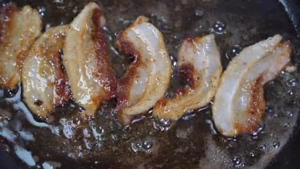 Färsk bacon sprutar i pannan. närbild av bacon — Stockvideo