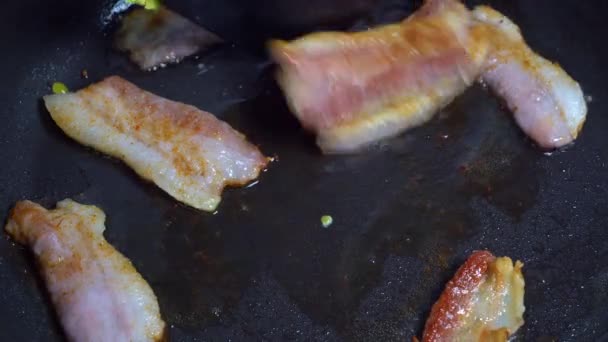 Färsk bacon sprutar i pannan. närbild av bacon — Stockvideo