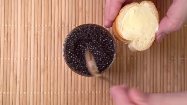 Verspreiding van zwarte kaviaar op brood en boter. kook apitizers — Stockvideo