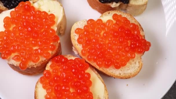 Aperitivos com caviar vermelho e preto perto giram em uma chapa — Vídeo de Stock