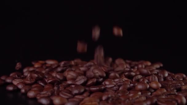 Granos de café tostados cayendo sobre fondo negro de cerca — Vídeo de stock