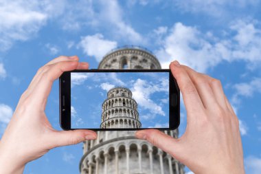 Bulutlu mavi gökyüzünün arka planında uzanan Pisa kulesi. Telefonda çekilmiş bir fotoğraf.