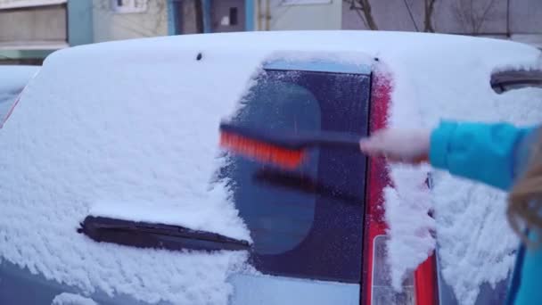 Femme nettoie la voiture de neige avec une brosse — Video