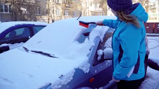 Mulher limpa o carro de neve com uma escova — Vídeo de Stock