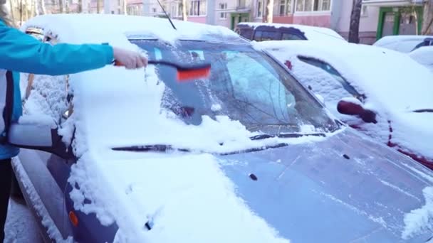 Женщина чистит машину от снега кистью — стоковое видео