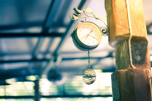 Reloj viejo colgando en un poste por la noche . — Foto de Stock