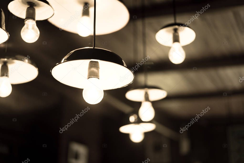 Many of the lamps hanging from the ceiling in a dark room.