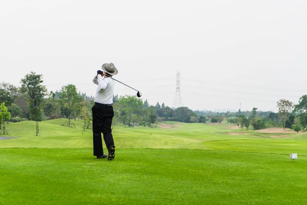 Stary człowiek sam golfa na zielone pole golfowe. — Zdjęcie stockowe