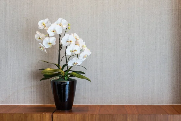 White flower vase placed on a wooden desk.