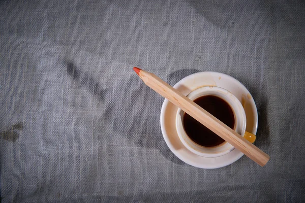 Eine Tasse Kaffee und ein Bleistift auf grauem Hintergrund. — Stockfoto