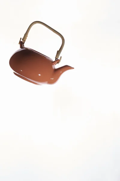 Flying orange teapot on white background.