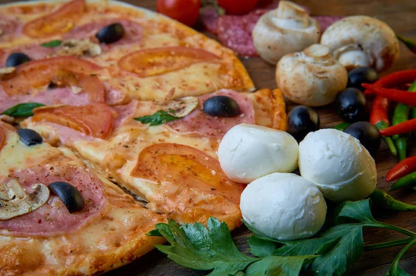 Pizza y diferentes ingredientes en ella. Fondo oscuro. Vista desde arriba . — Foto de Stock