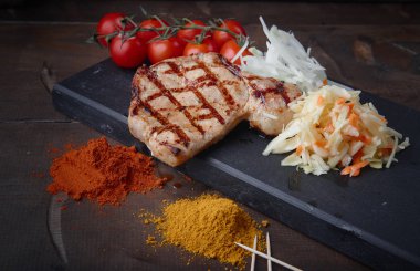 Çeşitli sebze ve baharat karanlık bir arka plan üzerinde ızgara domuz eti biftek.