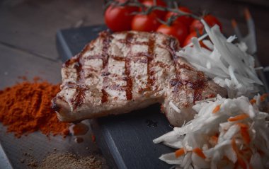 Çeşitli sebze ve baharat karanlık bir arka plan üzerinde ızgara domuz eti biftek.