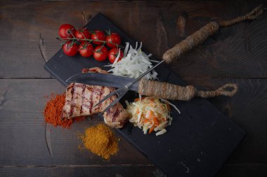 Çeşitli sebze ve baharat karanlık bir arka plan üzerinde ızgara domuz eti biftek.