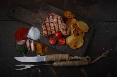 Çeşitli sebze ve baharat karanlık bir arka plan üzerinde ızgara domuz eti biftek.