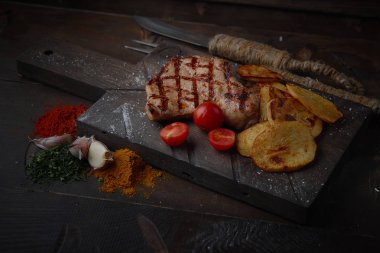 Çeşitli sebze ve baharat karanlık bir arka plan üzerinde ızgara domuz eti biftek.