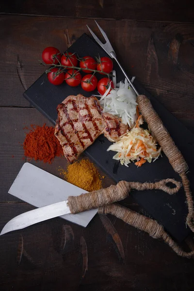 Çeşitli sebze ve baharat karanlık bir arka plan üzerinde ızgara domuz eti biftek.