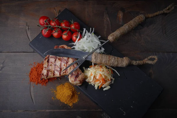 Çeşitli sebze ve baharat karanlık bir arka plan üzerinde ızgara domuz eti biftek.