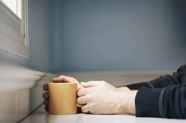 Hombre Sosteniendo Taza Café Naranja Mientras Está Sentado Cerca Ventana —  Fotos de Stock