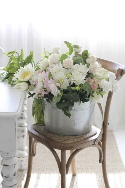 Wiadro Piękne Delikatne Kwiaty Krześle Pomieszczeniu — Zdjęcie stockowe